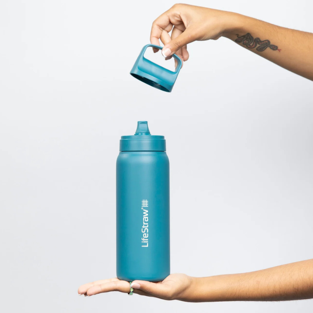 Teal water bottle with LifeStraw logo being held by a person against a light gray background